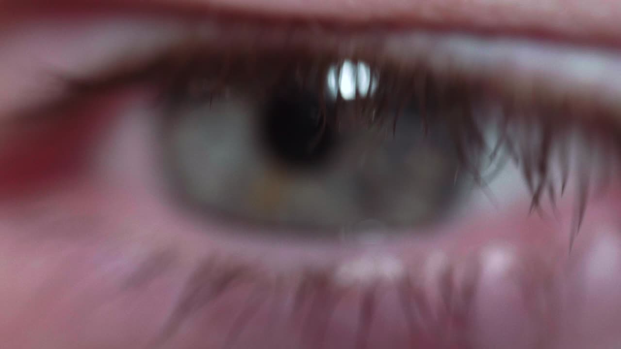 Reflection of screen on person's blue green eye in dark room 26