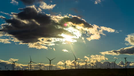 Windmühlen,-Die-Bei-Sonnenuntergang-Und-Einer-Farbenfrohen,-Goldenen-Wolkenlandschaft-Effiziente-Und-Saubere-Energie-Erzeugen---Weitwinkel-Zeitraffer