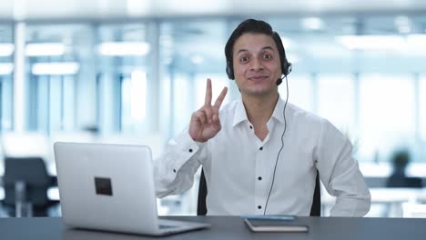 happy indian call center employee showing victory sign