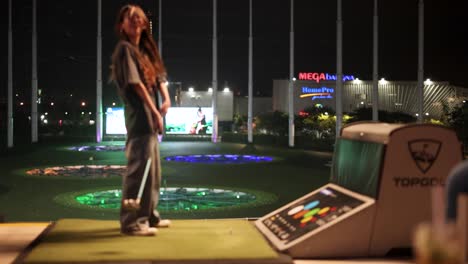 person practicing golf swings at driving range