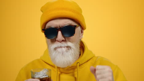 cheerful elderly man relaxing indoors. old guy drinking alcohol in studio.