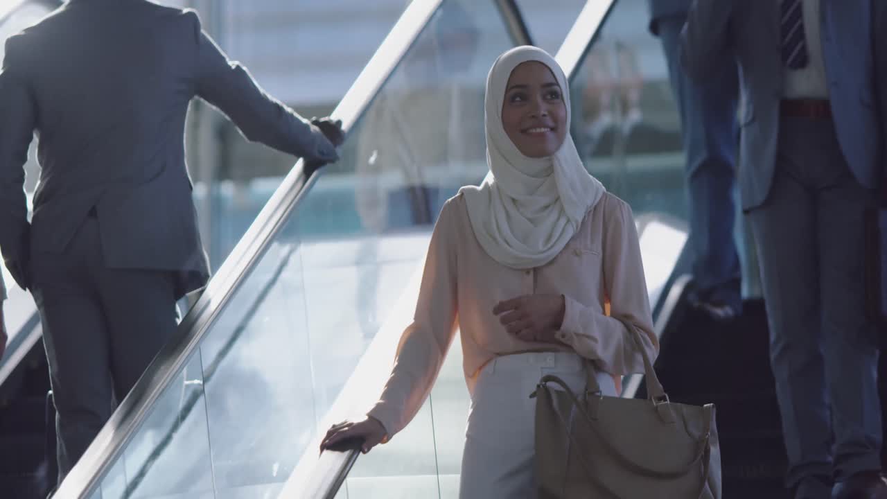 Businesswoman in hijab using escalator in a modern office 4k
