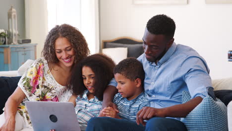 Zeitlupenaufnahme-Einer-Familie,-Die-Auf-Dem-Sofa-Sitzt-Und-Sich-Einen-Film-Ansieht,-Der-Auf-Dem-Laptop-Gestreamt-Wird