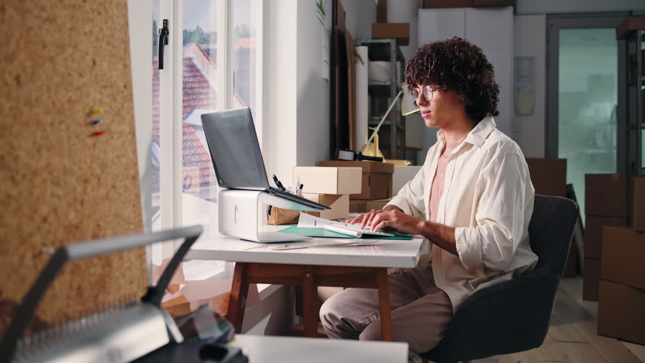 Giovane uomo che lavora al laptop e ai documenti in ufficio