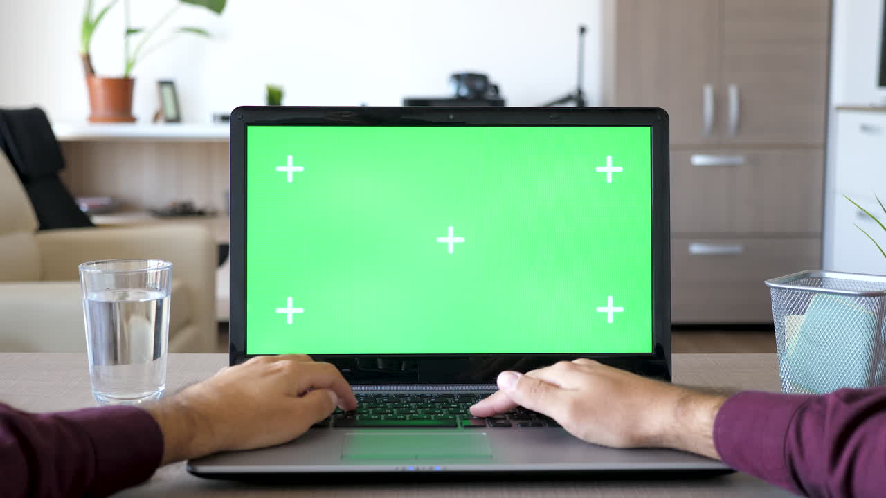 portátil con pantalla verde en un escritorio