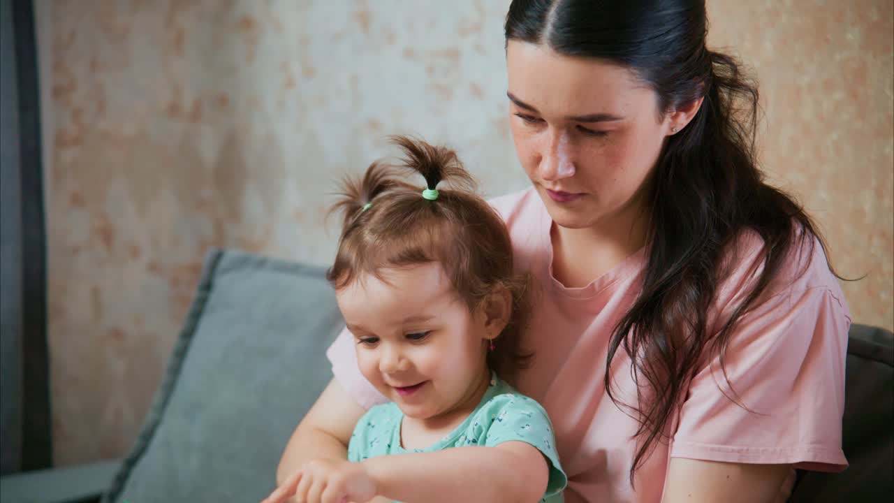 A nurturing moment shared between a mother and her young daughter, as they engage in a playful activity, fostering connection and joy in a cozy indoor setting