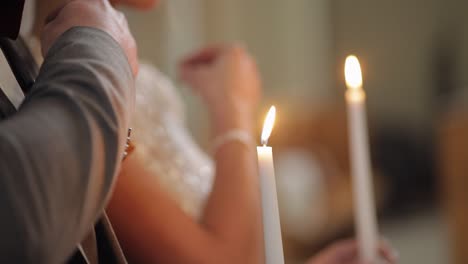 Los-Recién-Casados,-La-Novia-Y-El-Novio-Se-Paran-Y-Rezan-En-La-Iglesia,-Sosteniendo-Velas-En-Las-Manos,-Ceremonia-De-Boda