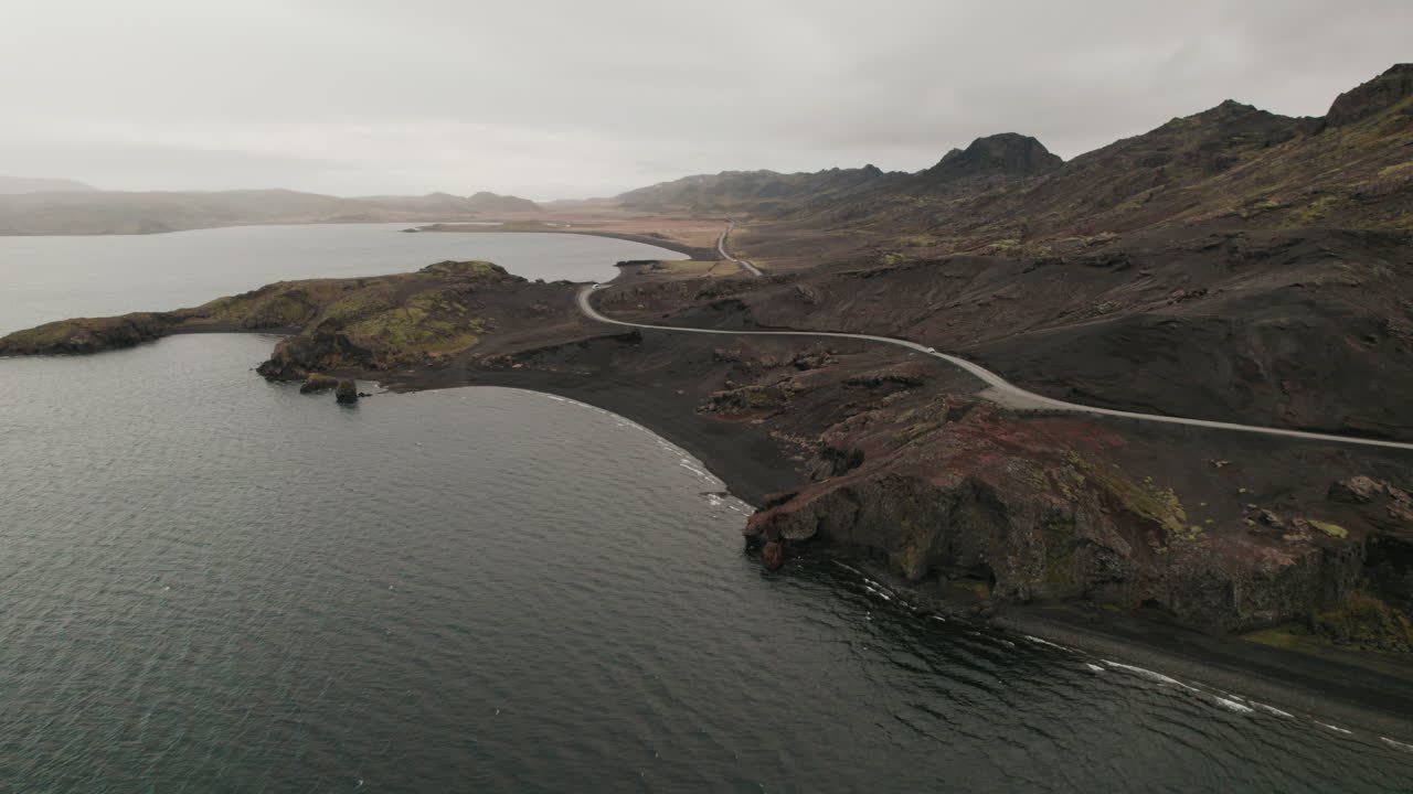 elevación aérea por encima de la sinuosa carretera que recorre la orilla del lago en islandia