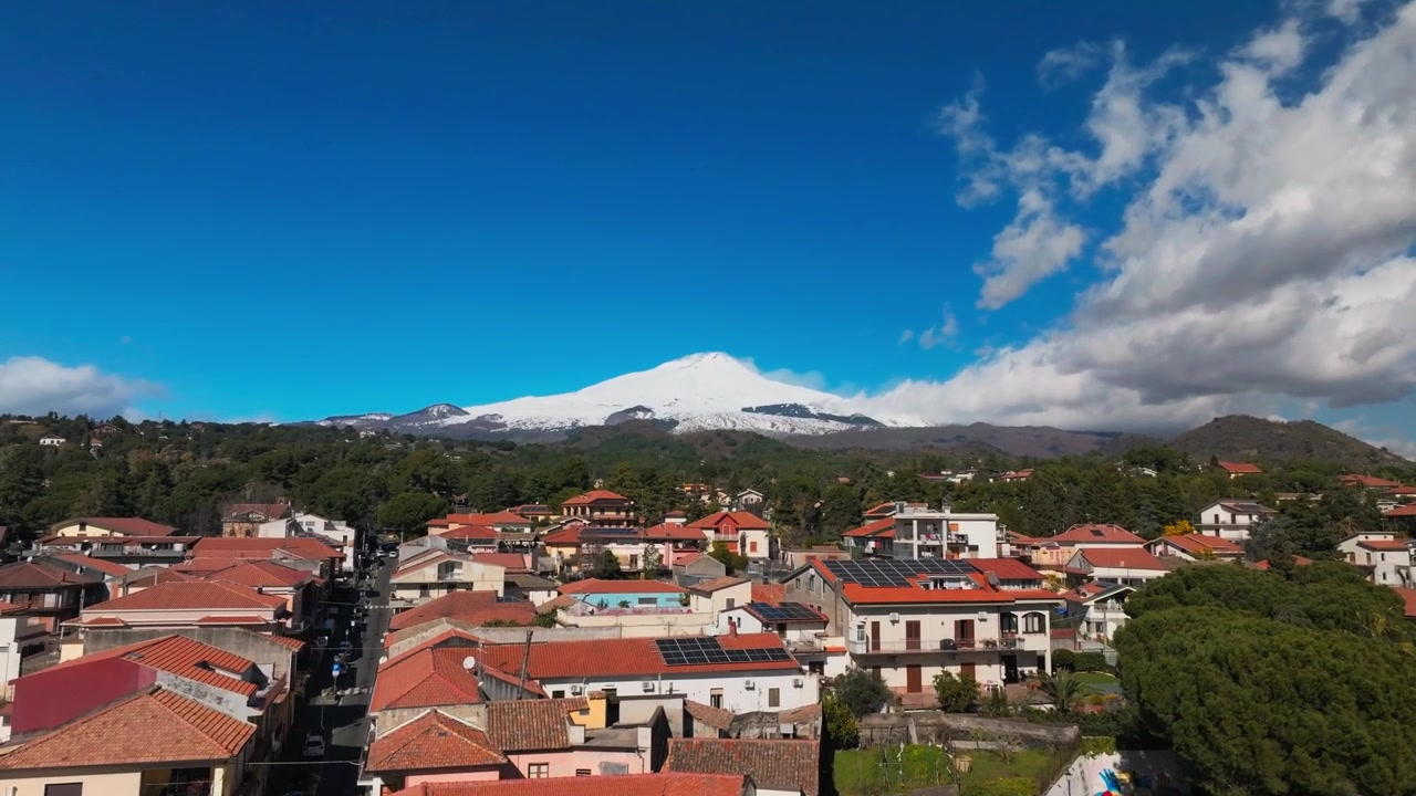 Case residenziali e strada a Catania con l'Etna innevato sullo sfondo in Sicilia, Italia. - ripresa aerea