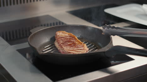 turning beef steak over in grilled pan