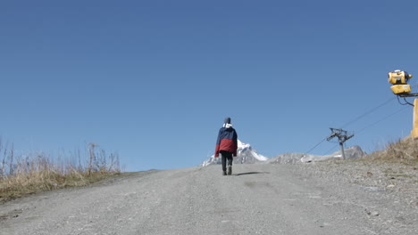 child walking up a mountain path at a ski resort on a sunny spring day