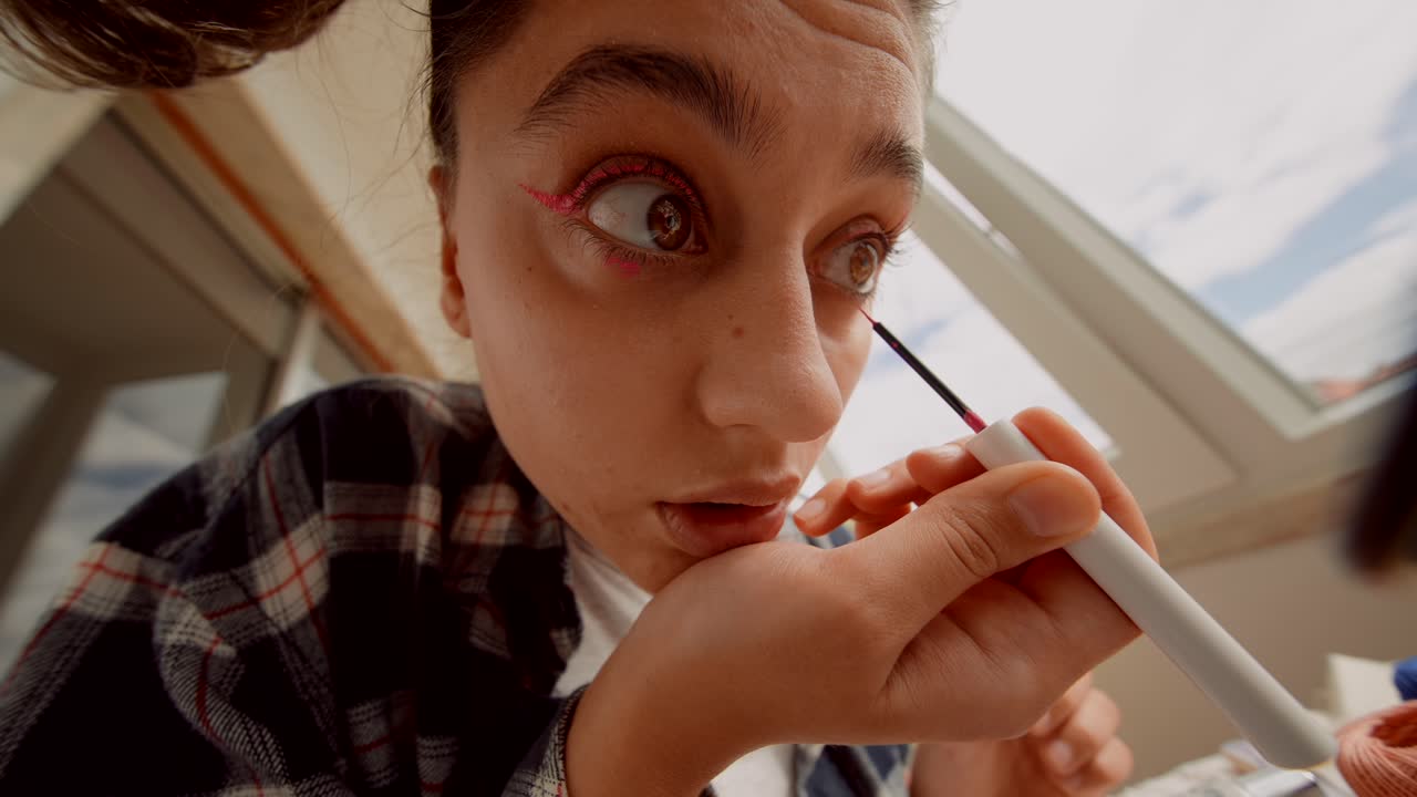 Primo piano di giovane donna che applica eyeliner rosa vivace