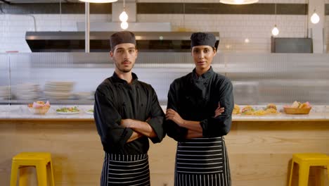 Male-and-female-chef-standing-with-arm-crossed-in-caferia-4k