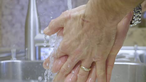 slow motion of person washing his hands with soap in silver sink, personal hygiene