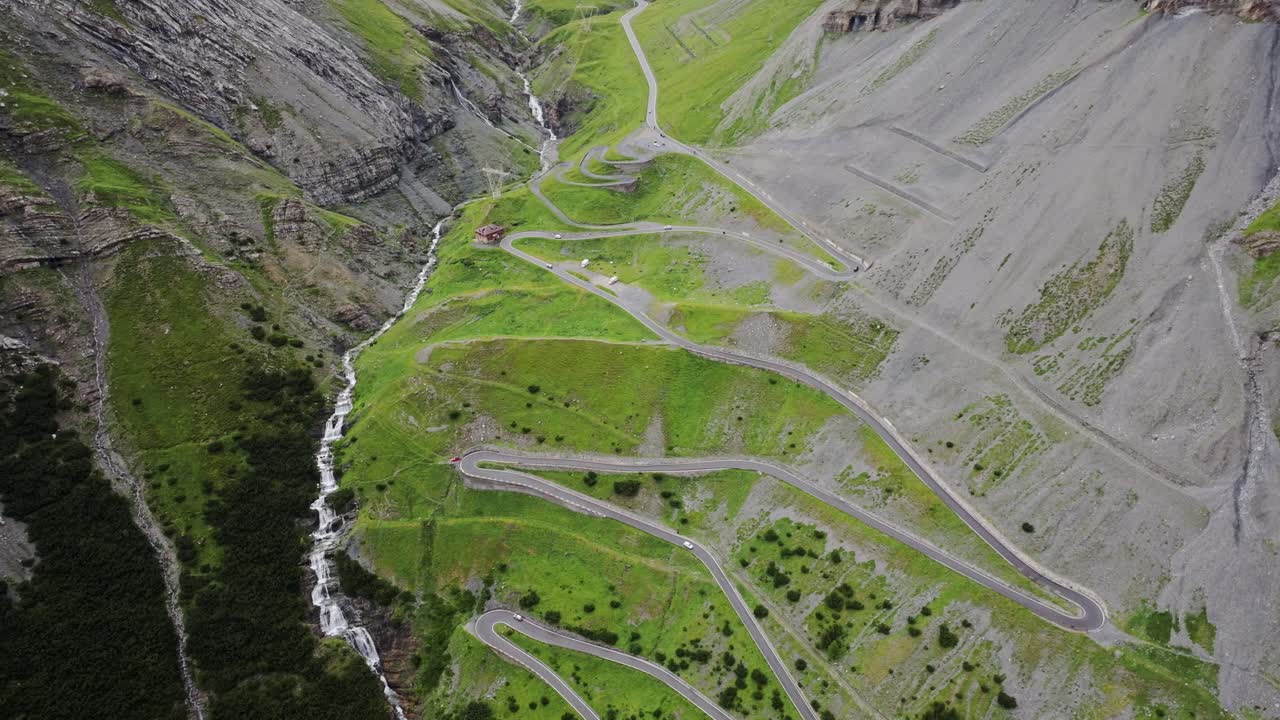 Epic aerial of rugged Stelvio Pass, thunderous Cascata del Braulio, rocky slopes