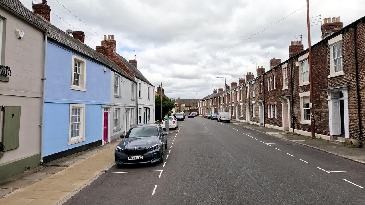 Empty street lined with brick houses and parked cars