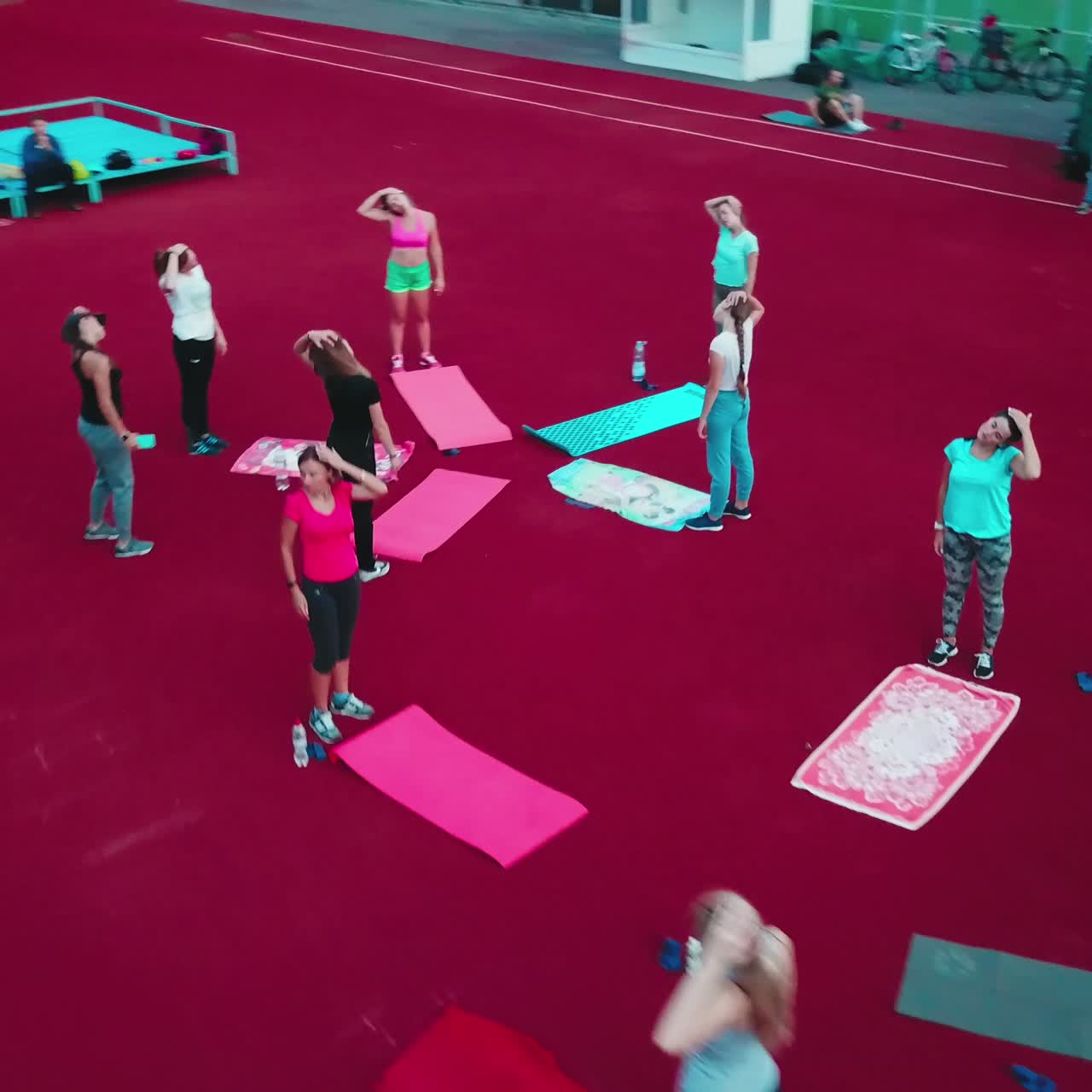 Women having a rest after workout. Group of fitness girls doing exercises on the outdoor stadium. Drone view.