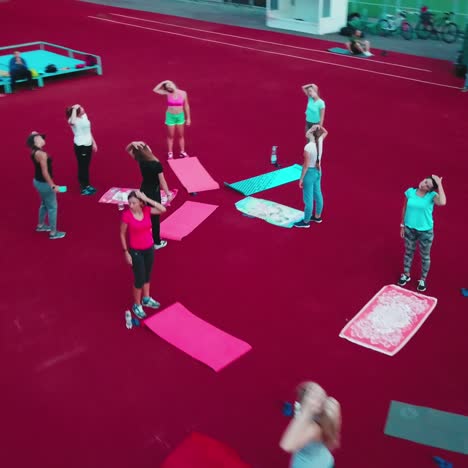 women having a rest after workout. group of fitness girls doing exercises on the outdoor stadium. drone view.
