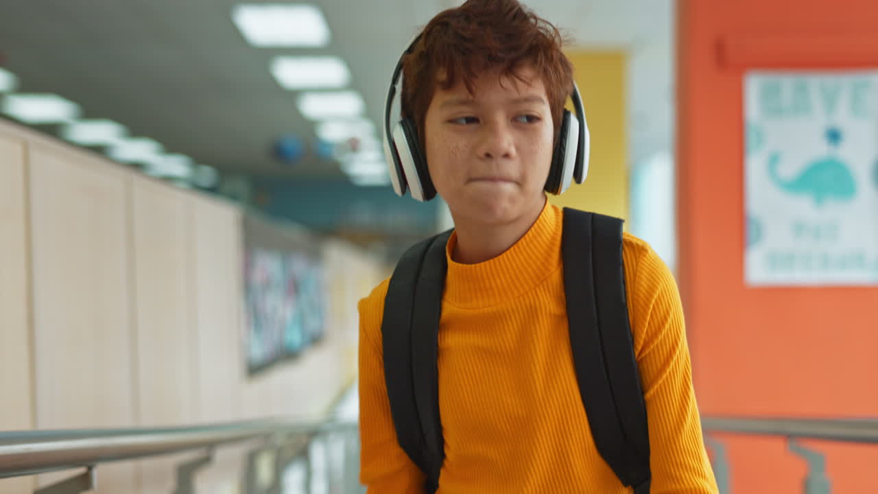 Teenage student with headphones and backpack in school hallway