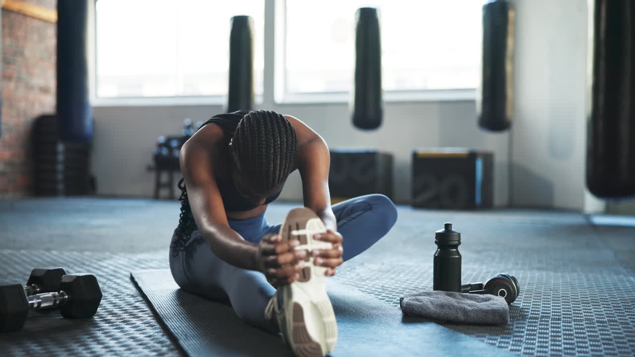 Kebugaran, gym, dan wanita berkulit hitam melakukan peregangan di lantai