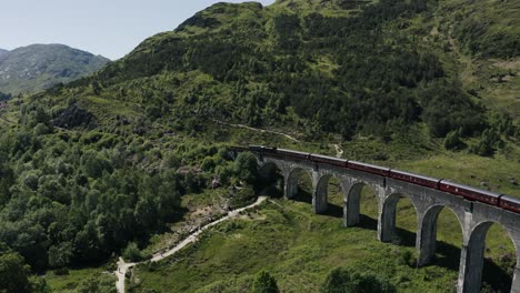 drone shot of a train traveling through scotland's green hills