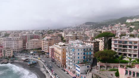 coastline of genoa cityscape with rolling foggy clouds over it, aerial fly backward view