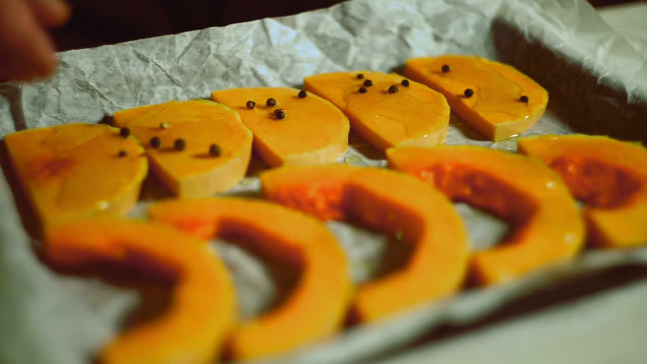 가까운 남자 손은 베이킹 시트에 고추 호박 조각을 부어. 건강한 음식