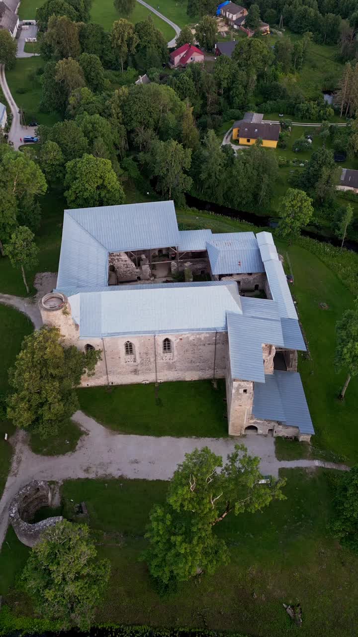 Vertical drone video of Padise Monastery estate with its impressive stone ruins historic architecture and lush green landscapes providing a stunning view of this important Estonian heritage site
