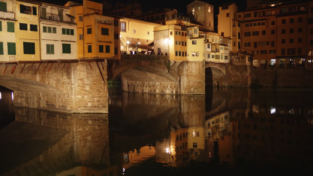 Ponte Vecchio illuminato di notte con il riflesso del fiume