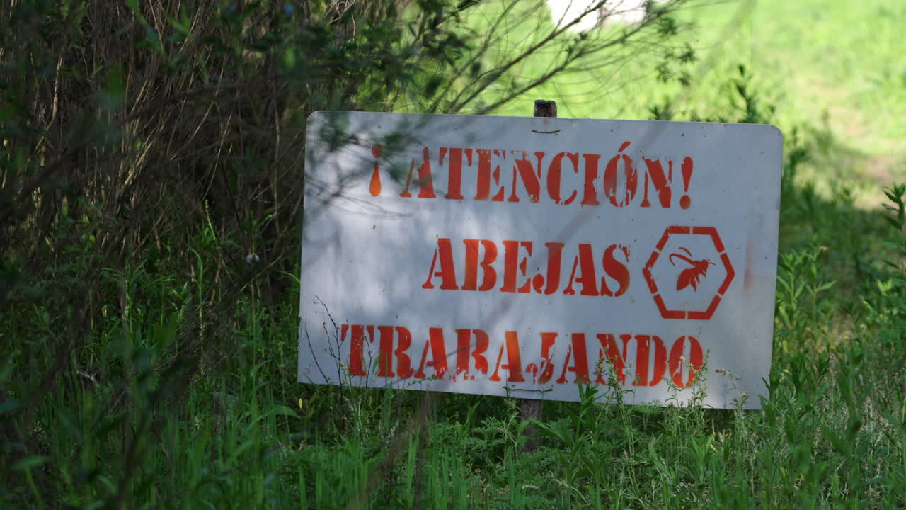 Warning sign in Spanish that says "Caution Bees at Work" in rural field