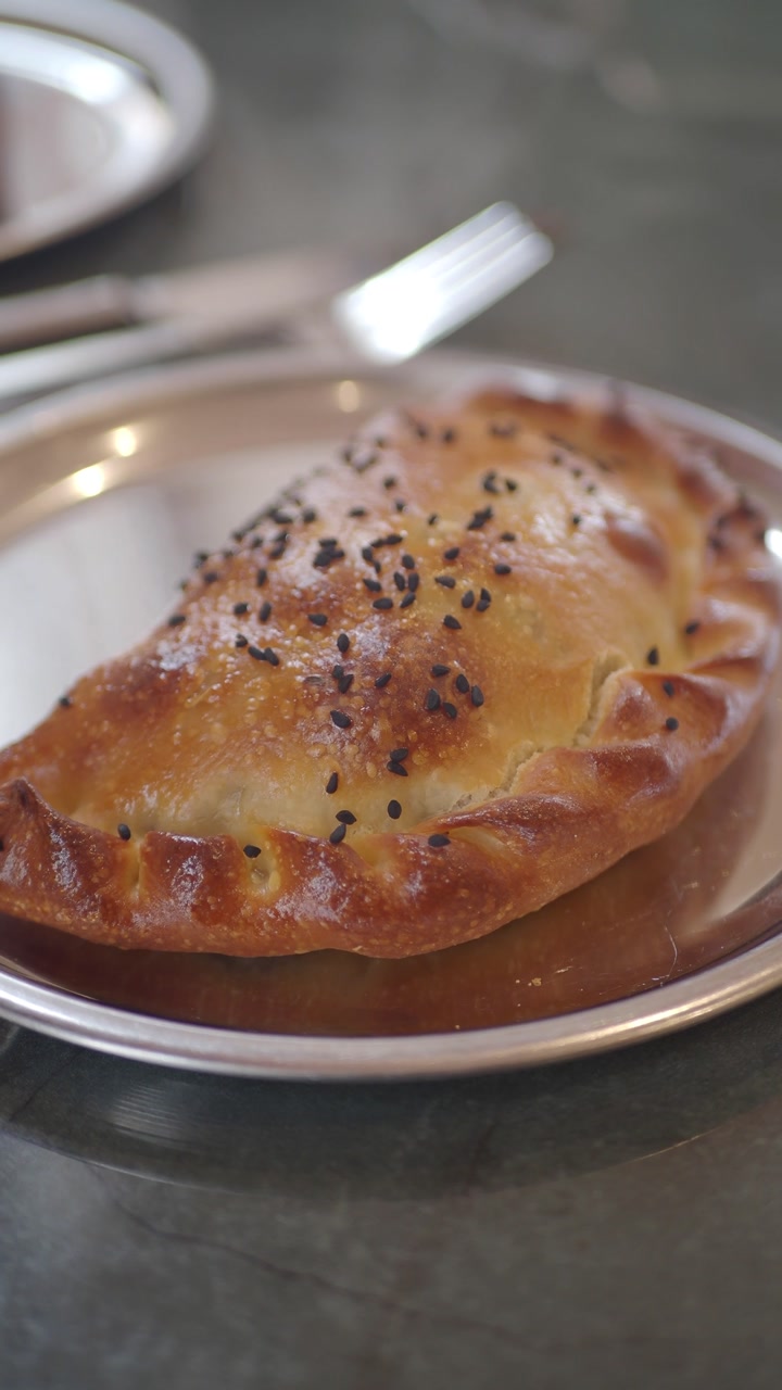 Golden Brown Savory Pastry with Black Sesame Seeds on a Plate