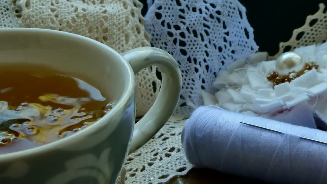 Versare l'acqua in una tazza di tè su un vassoio con materiali da cucito