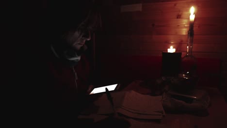 woman using smartphone hand writing paper, candle light in dark room