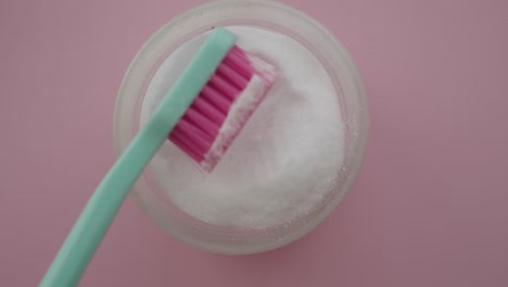 toothbrush dipping into white powder in a bowl