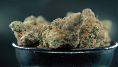 una macro pan de ensueño a la derecha de una planta de cannabis, variedades híbridas de naranja, sativa, flor de marihuana, en un soporte giratorio, cámara lenta, video 4k, iluminación de estudio