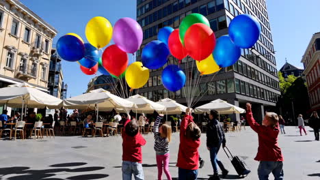 children with balloons in city square