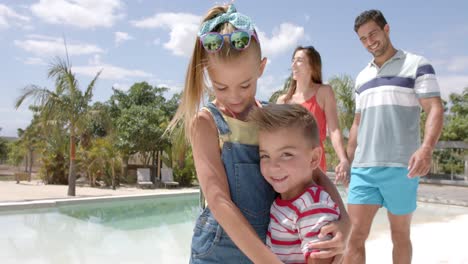 portrait of happy caucasian family walking at swimming pool at beach house