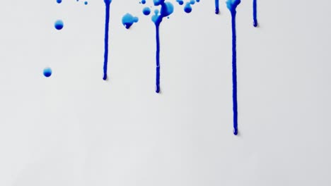 Close-up-of-blue-paint-shapes-on-white-background-with-copy-space,-slow-motion