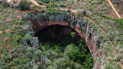 toma aérea giratoria de drones de la gran entrada de la cueva lapa doce de rocas coloridas con una selva tropical autónoma debajo en el parque nacional chapada diamantina en bahia, noreste de brasil