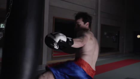 aggressive kickboxer punching the heaby bag in an empty gym