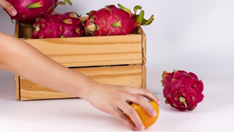 hands placing fruits into a wooden crate