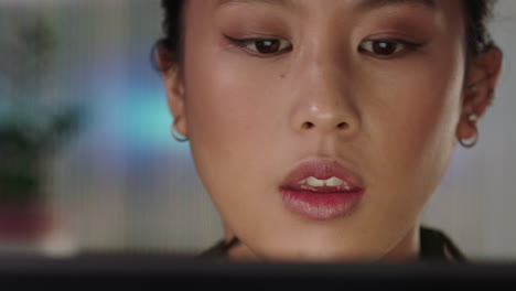 close up portrait beautiful asian business woman working late using tablet computer browsing financial graph data looking at information on screen wearing glasses