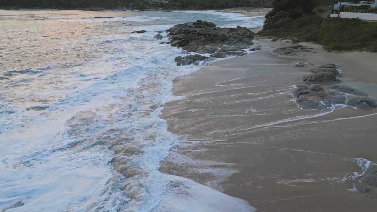 White sand beach with breaking waves at the rocks