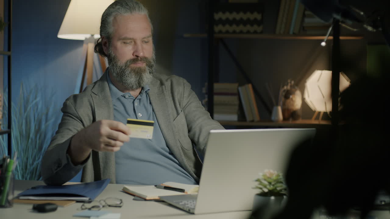 Uomo che usa laptop e carta di credito di notte