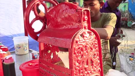 local using red hand cranked ice shaving machine on stall in street in chittagong