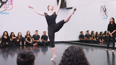 female ballet student at performing arts school performs for class and teacher in dance studio