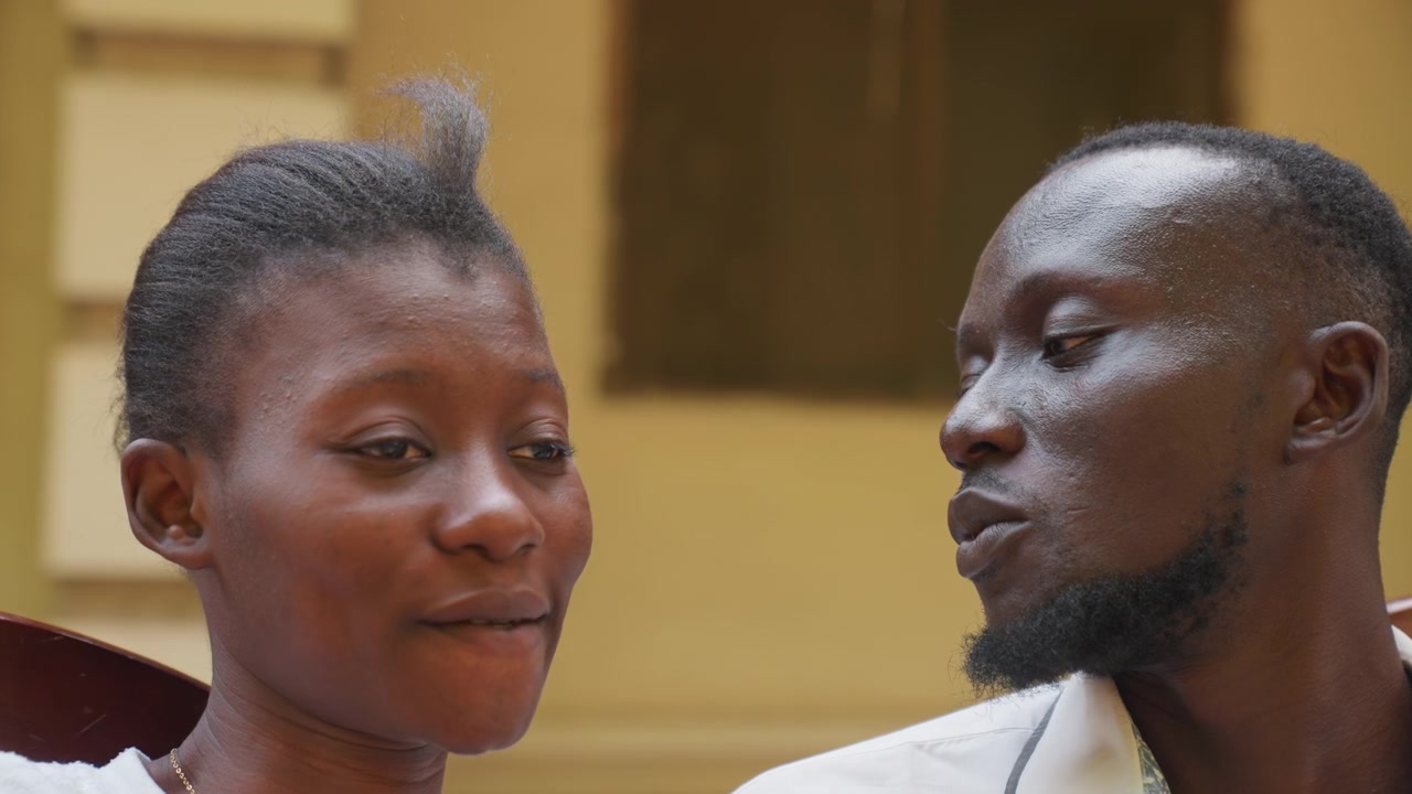 Couple s'étreignant avec affection. Moment romantique sur un porche ensoleillé. Étudiants échangeant un regard tendre sous la lumière chaude du soleil. Couple intime sur le porche d'un campus affichant une douce affection et des sourires timides