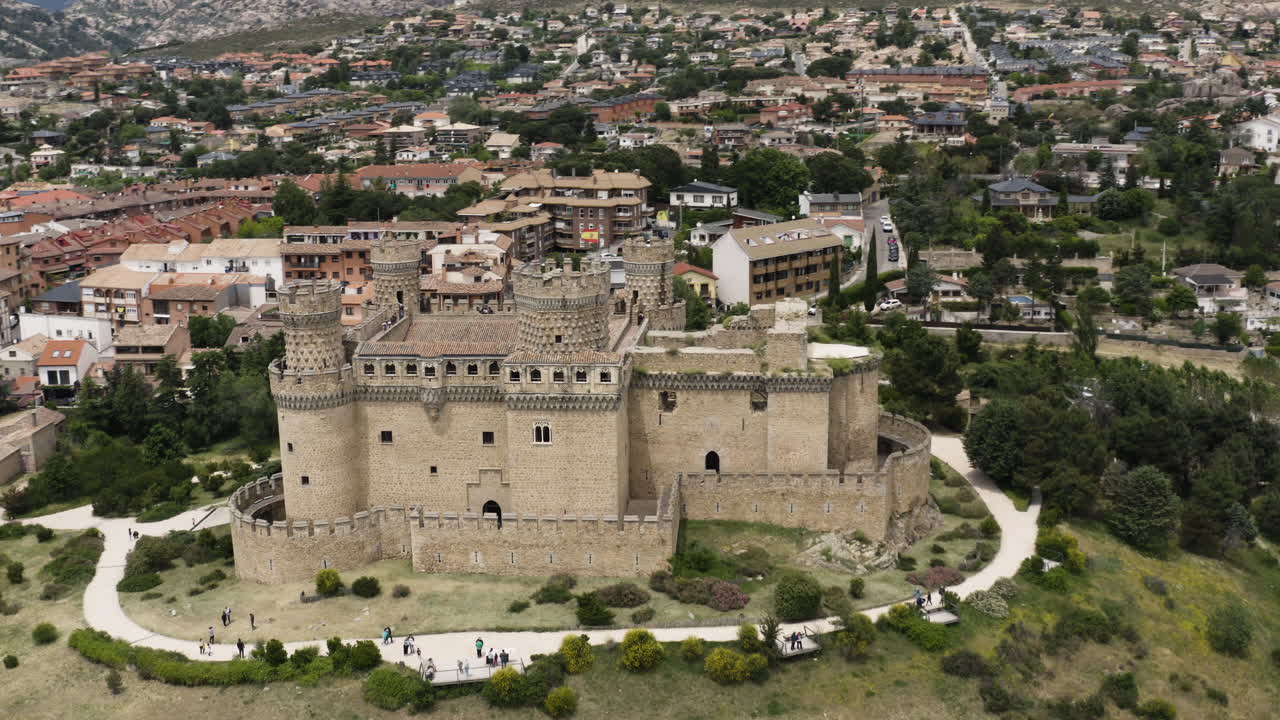 antena sobre el nuevo castillo de manzanares el real con una suave inclinación hacia arriba para revelar la ciudad circundante y las impresionantes estribaciones de la sierra de guadarrama