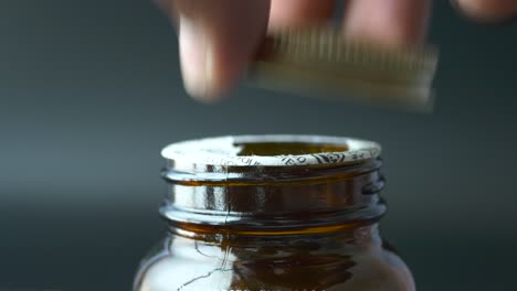 hand opening a brown glass bottle