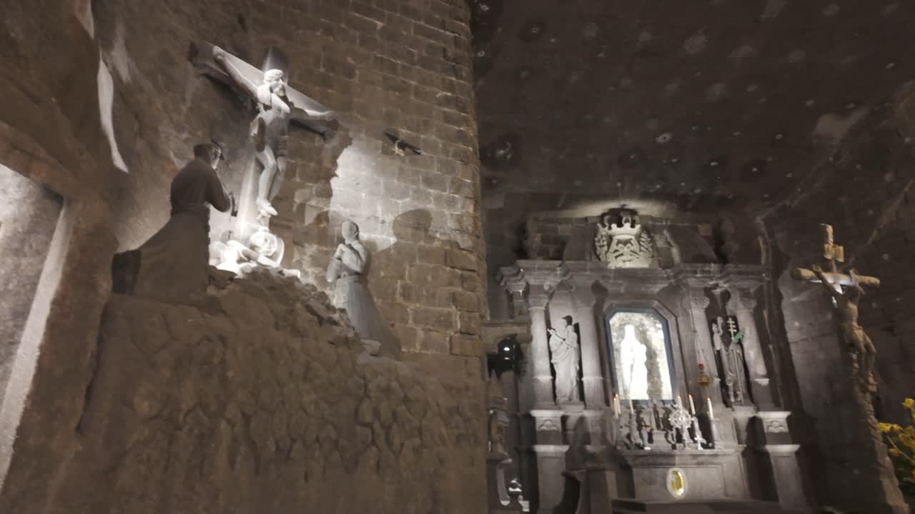 Ancient salt mine chamber with religious statues and carved stone walls in Krakow, Poland
